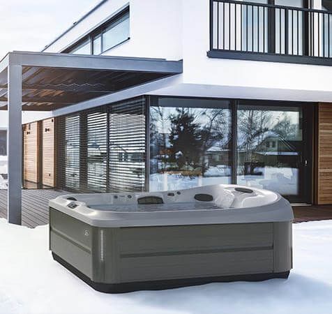 Un bain à remous est posé dans la neige devant une maison.