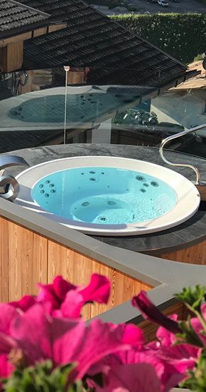 Un spa rempli d'eau bleue est entouré de fleurs roses.