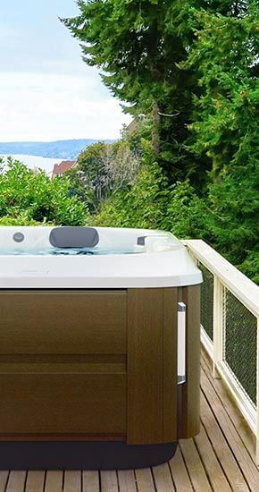 Un spa est installé sur une terrasse en bois surplombant l'océan.