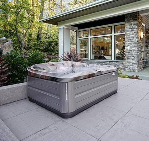 Un bain à remous est installé sur une terrasse devant une maison.