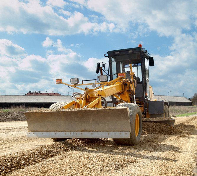 A Yellow Tractor Is Driving Down a Dirt Road — CK's Milling & Earthworks in Veteran, QLD
