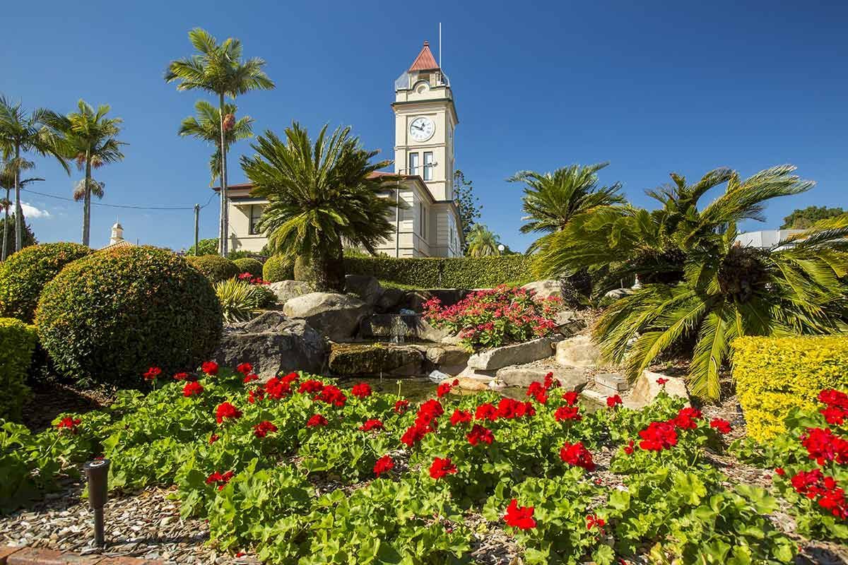 A Clock Tower Is Surrounded by Flowers and Trees in A Park — CK's Milling & Earthworks in Gympie, QLD