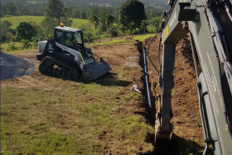 A Bulldozer Is Digging a Hole in The Ground in A Field — CK's Milling & Earthworks in Bells Bridge, QLD