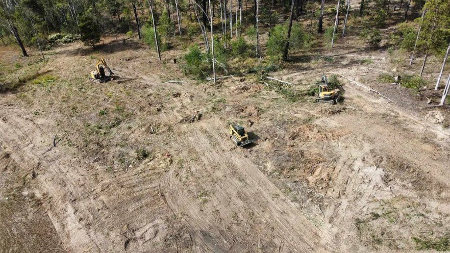 An Aerial View of A Person Riding an ATV on A Dirt Road in The Woods — CK's Milling & Earthworks in Bells Bridge, QLD