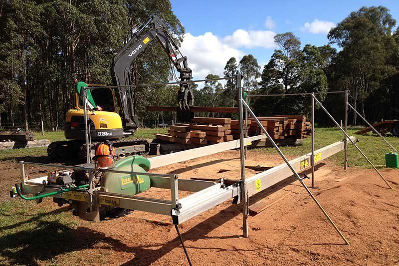A Yellow Excavator Is Sitting on Top of A Trailer in A Field — CK's Milling & Earthworks in Maryborough, QLD