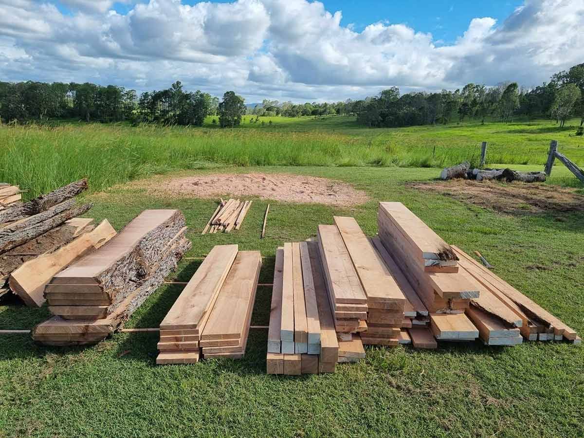 A Pile of Wood Is Sitting on Top of A Lush Green Field — CK's Milling & Earthworks in Bauple, QLD