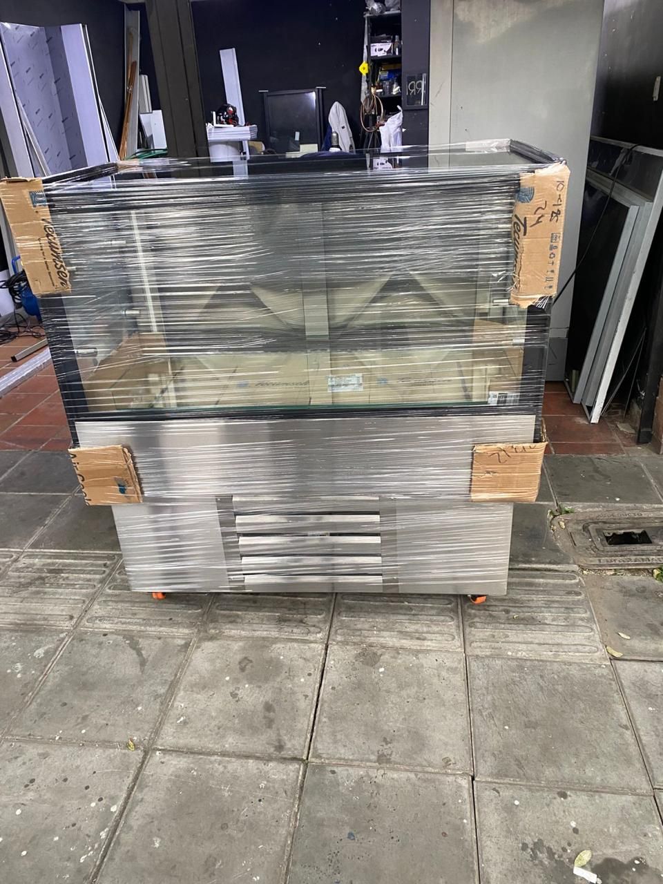 Palé envuelto en plástico retráctil con productos embalados en el suelo de un almacén, con protectores de cartón