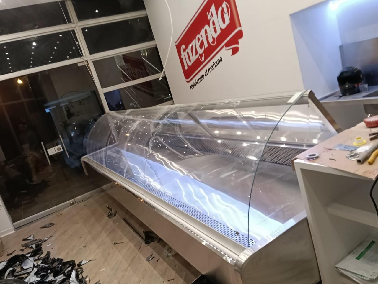 Vitrina vacía de una panadería en el interior luminoso de una tienda con un letrero rojo en la pared.