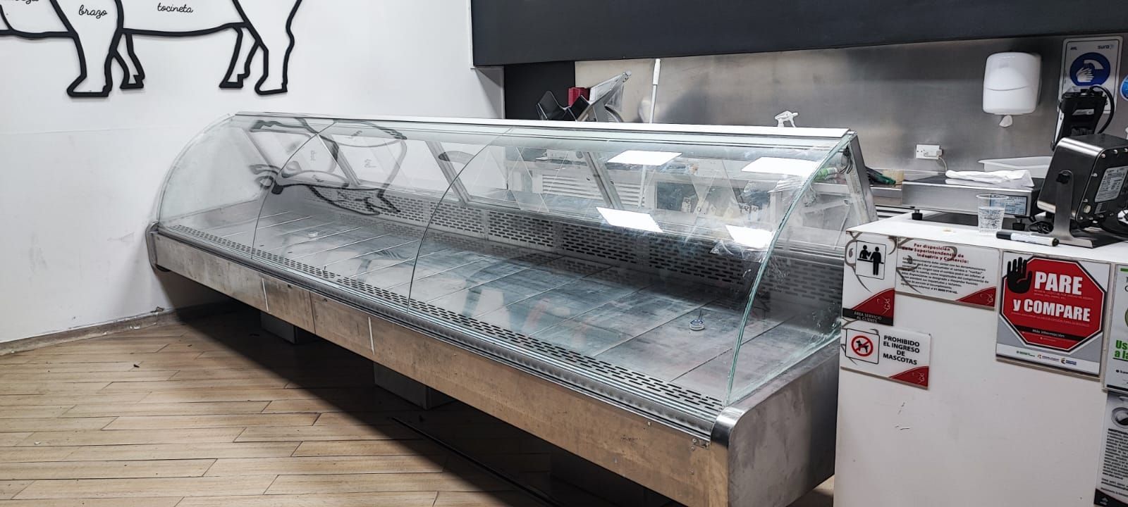 Vitrina larga para charcutería con cubierta de plástico transparente en el interior luminoso de una tienda.