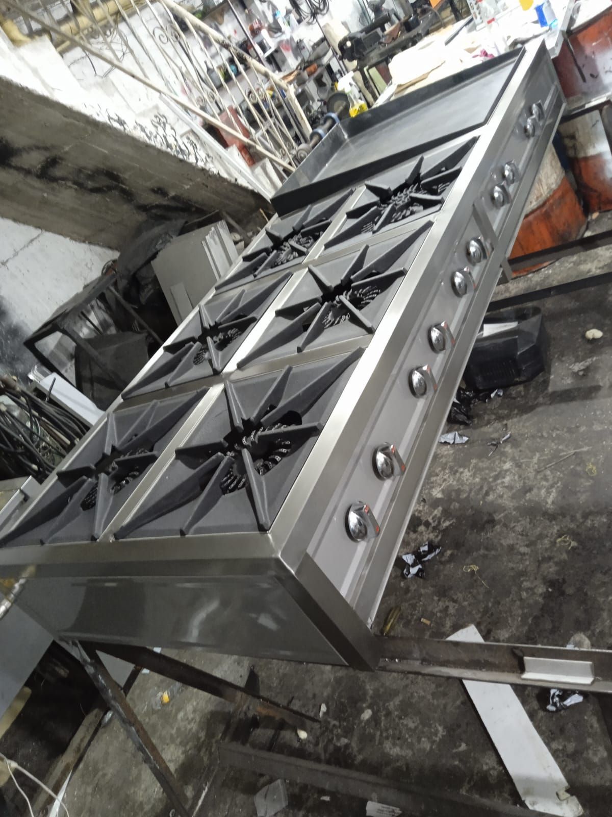 Horno industrial de acero inoxidable en el suelo de una fábrica, inclinado de lado.