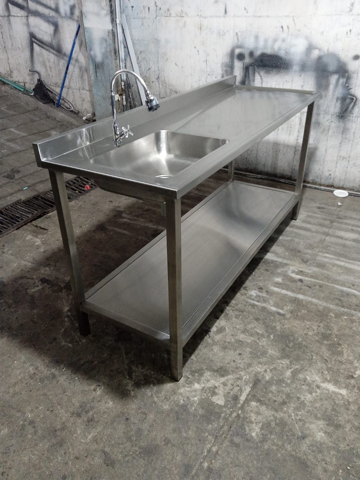 una mesa con fregadero de acero inoxidable, grifo