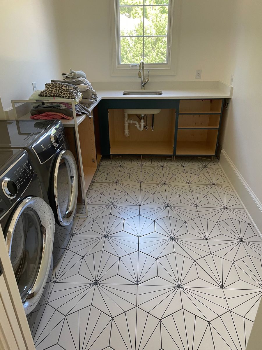 Laundry room with washer and dryer, patterned tile floor, and a utility sink under a window