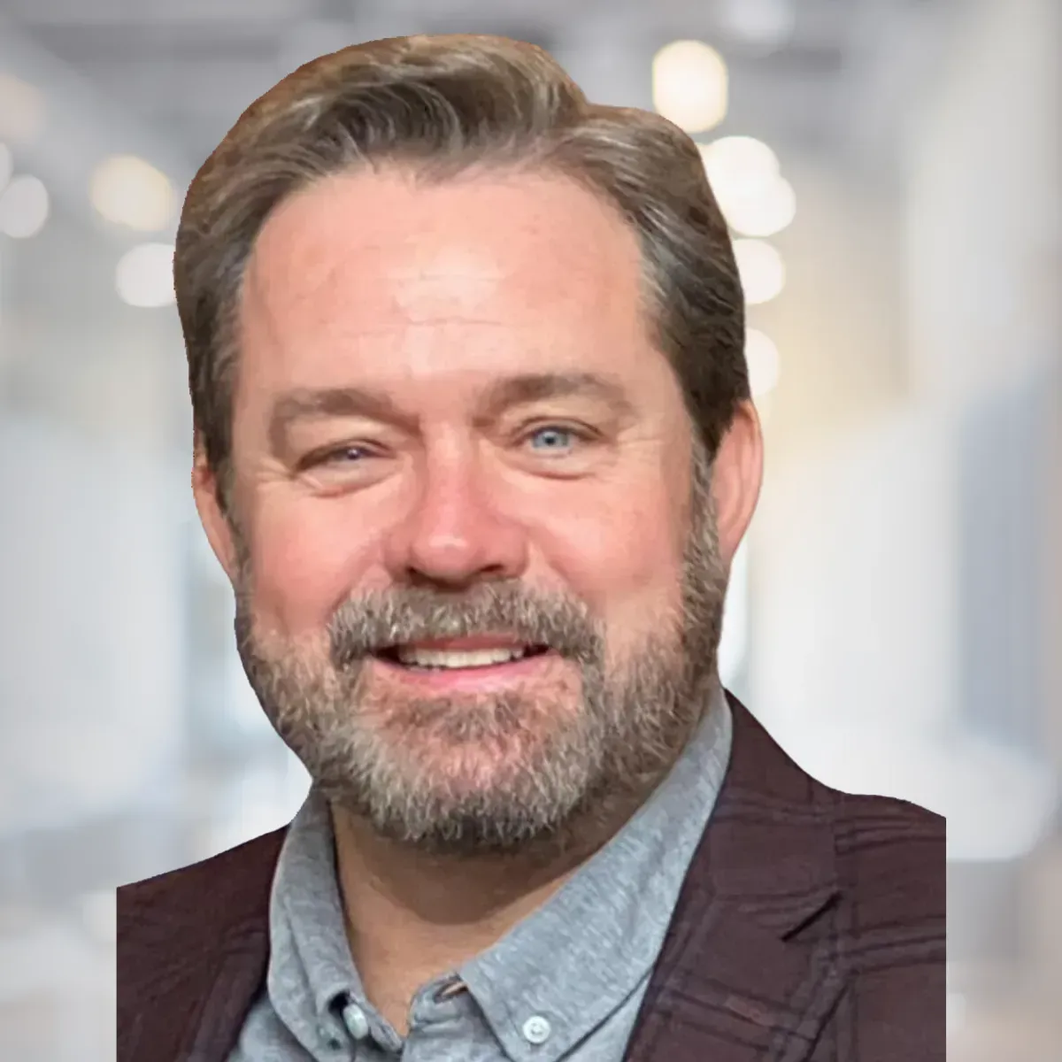 A man with a beard and a suit is smiling for the camera.