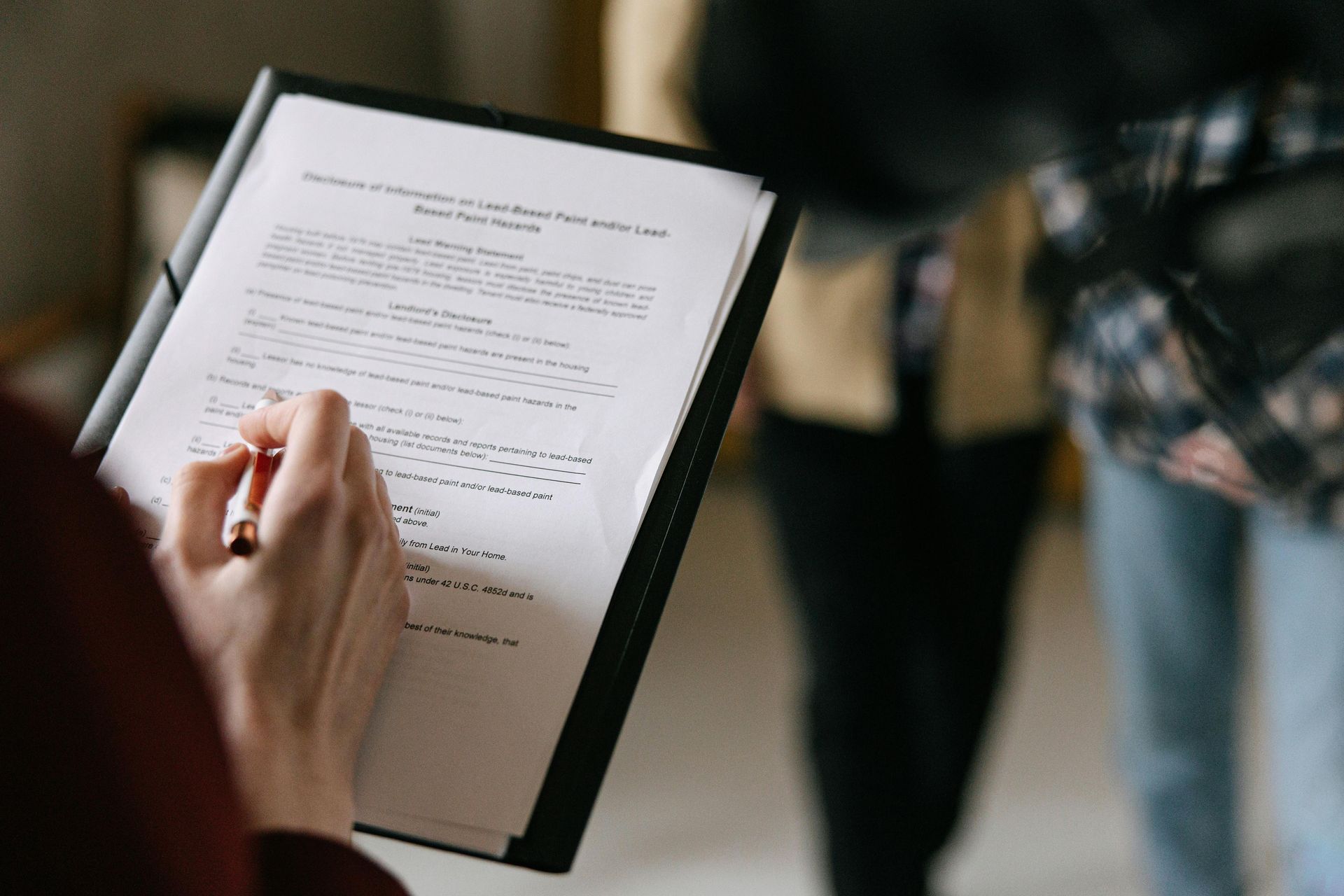 A person is holding a clipboard with a pen in their hand.