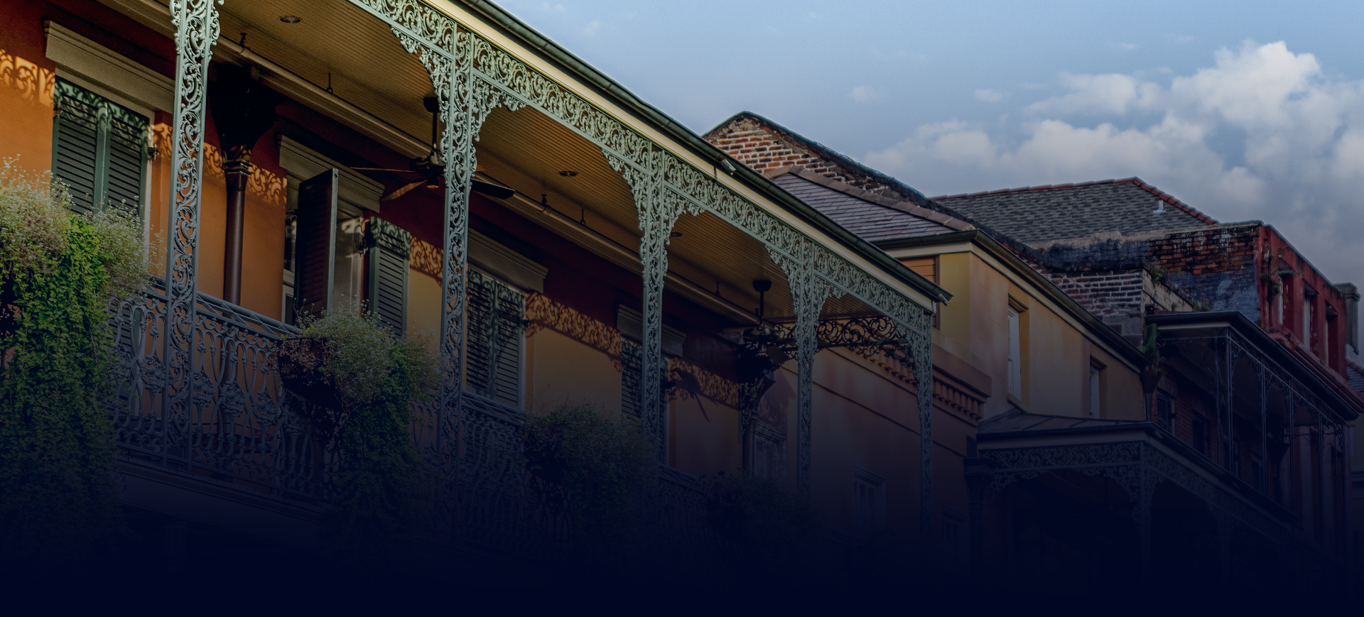 Balcony-lined historic building at dusk with cloudy sky and dark foreground