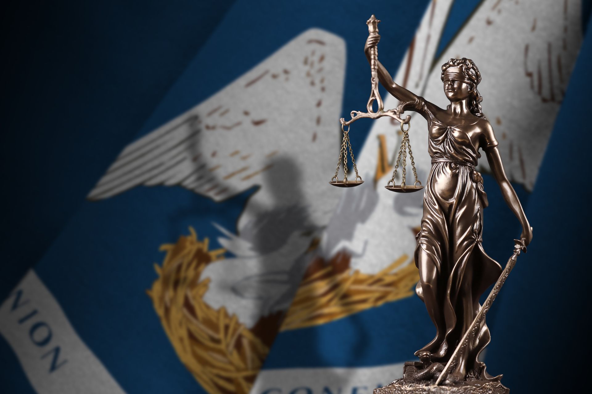 Bronze Lady Justice figurine before a blue U.N. flag with white dove and olive branch symbols