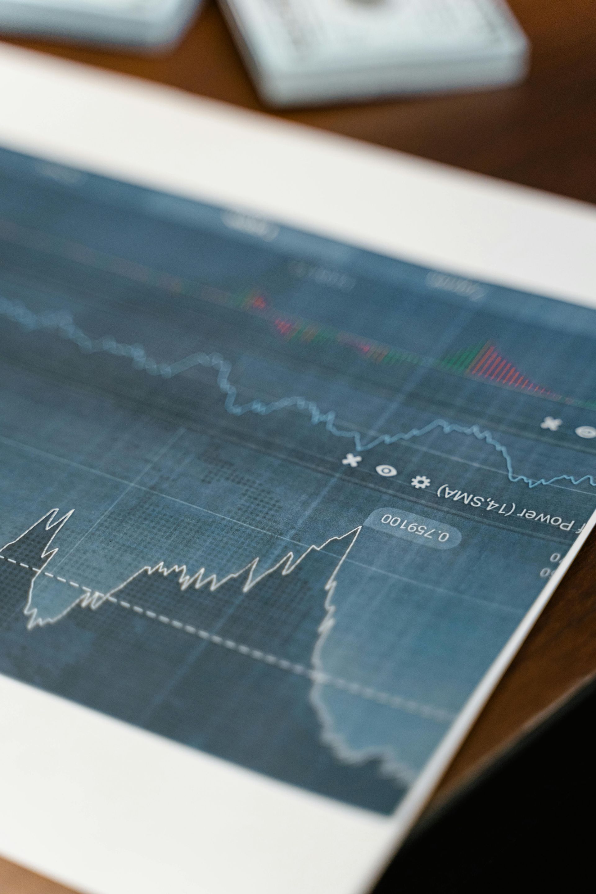 Close-up of a stock market chart on a desk with blue graph lines and a laptop in the background