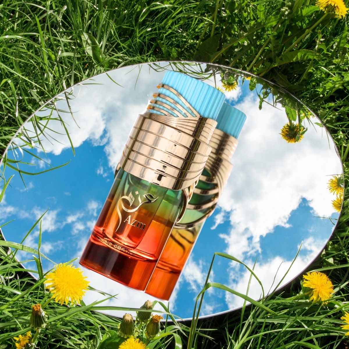 A perfume bottle with rainbow colors on a mirror reflecting a blue sky with clouds, surrounded by grass and flowers.