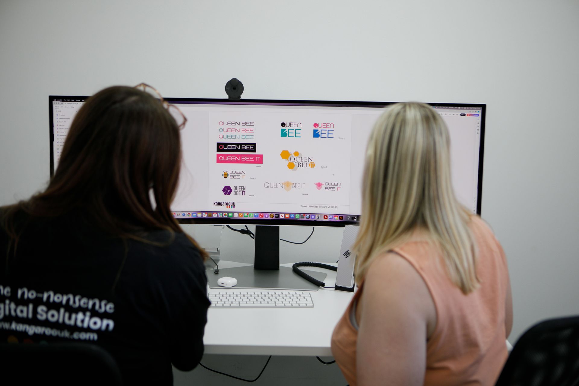 Two women looking at a computer screen, discussing content in an office setting.