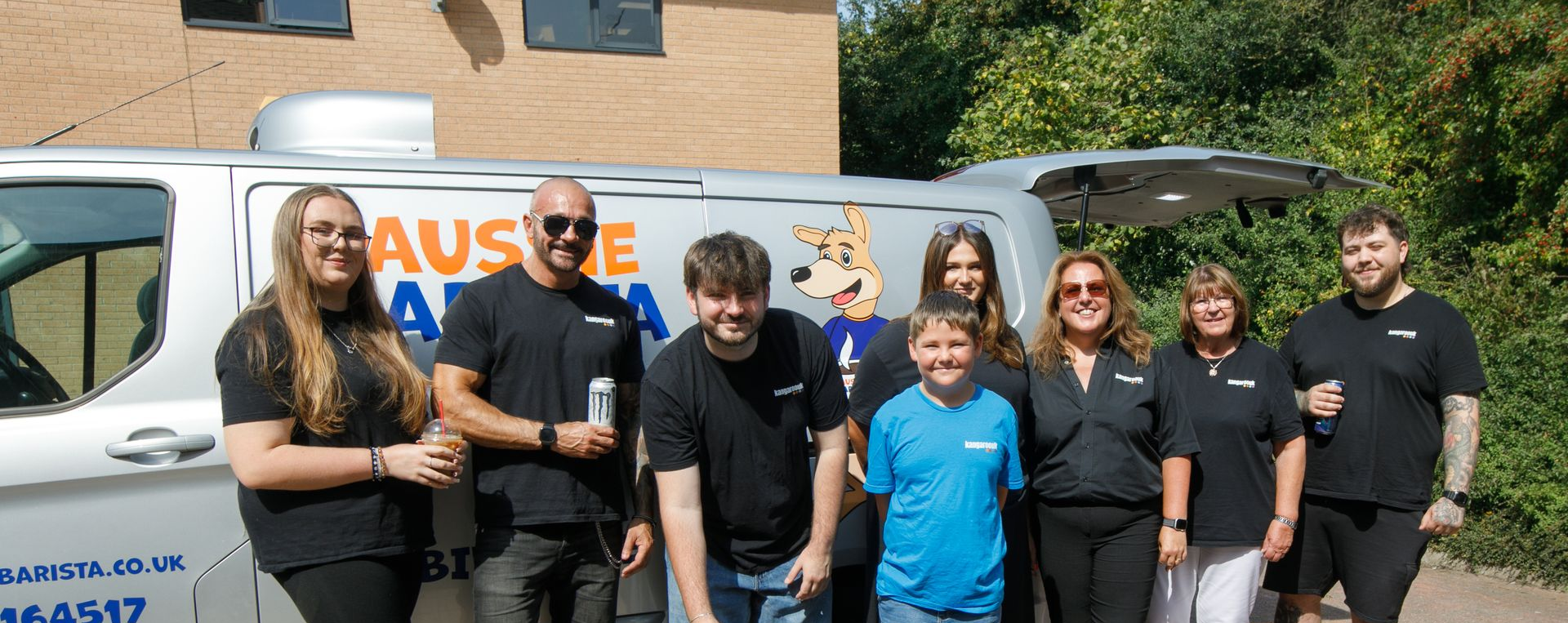 A group of people in front of a van. Most wear black shirts. The van has the company name