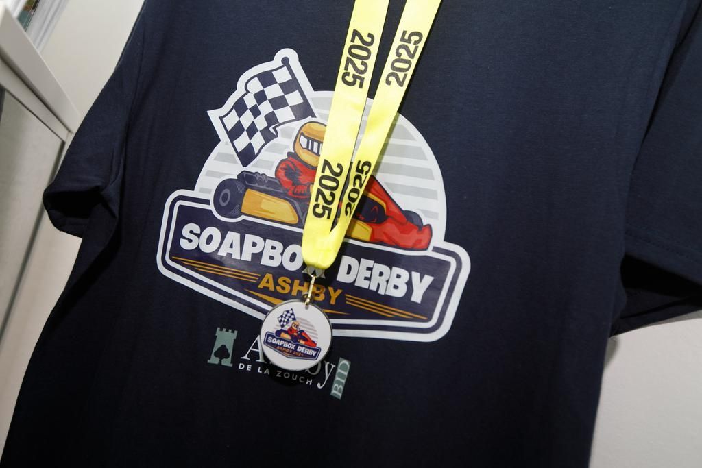 Black t-shirt with a Soapbox Derby logo and a medal with a yellow 2025 lanyard.