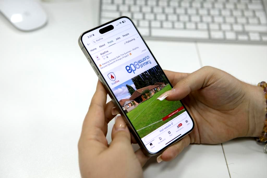 Person holding a smartphone showing a website with a nature scene, likely a travel site.