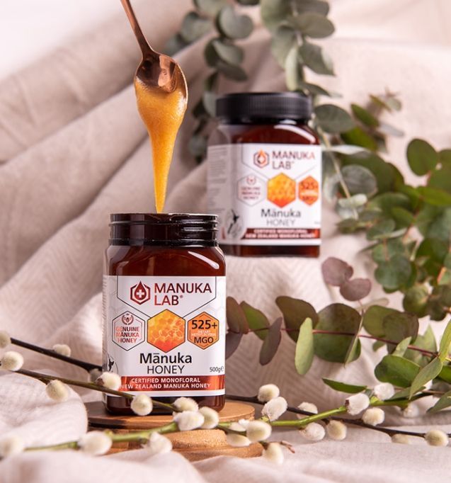 Two jars of Manuka honey with spoon pouring honey.