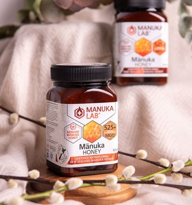Two jars of Manuka Lab honey. One is in focus in the foreground, with label details visible.