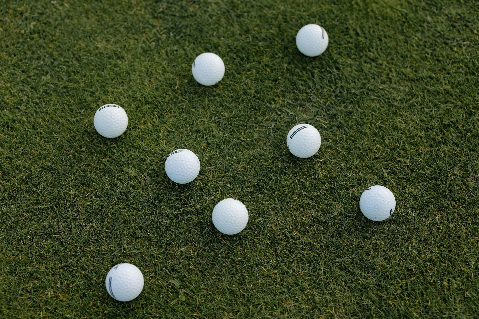 A group of golf balls are sitting on top of a green field.