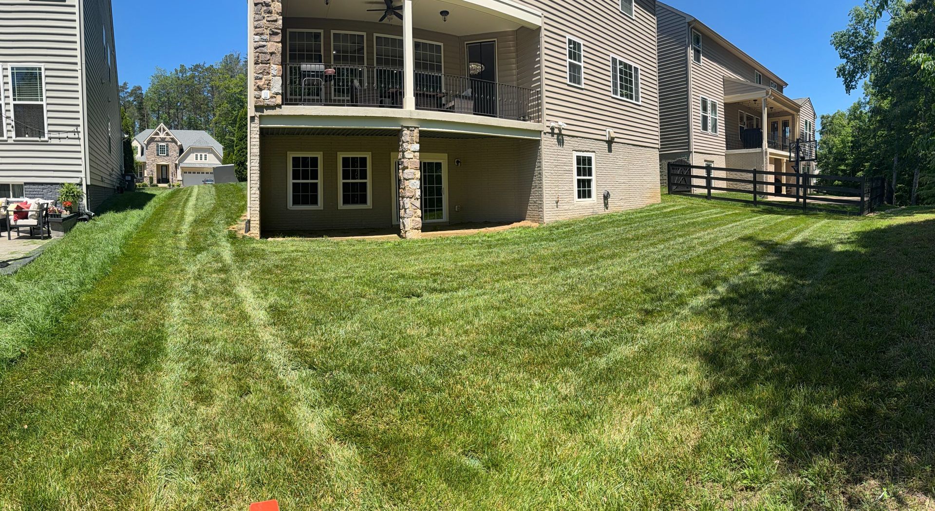 Apartment building with green lawn, patio, and a narrow grassy path under a blue sky