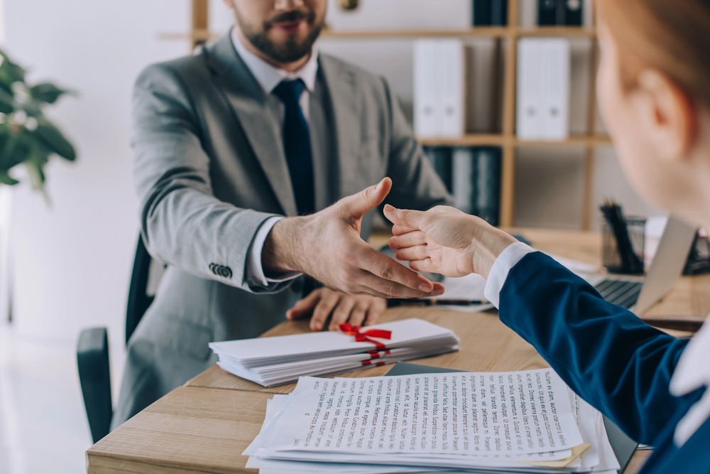 Dos empresarios dándose la mano por encima de un escritorio en una oficina.