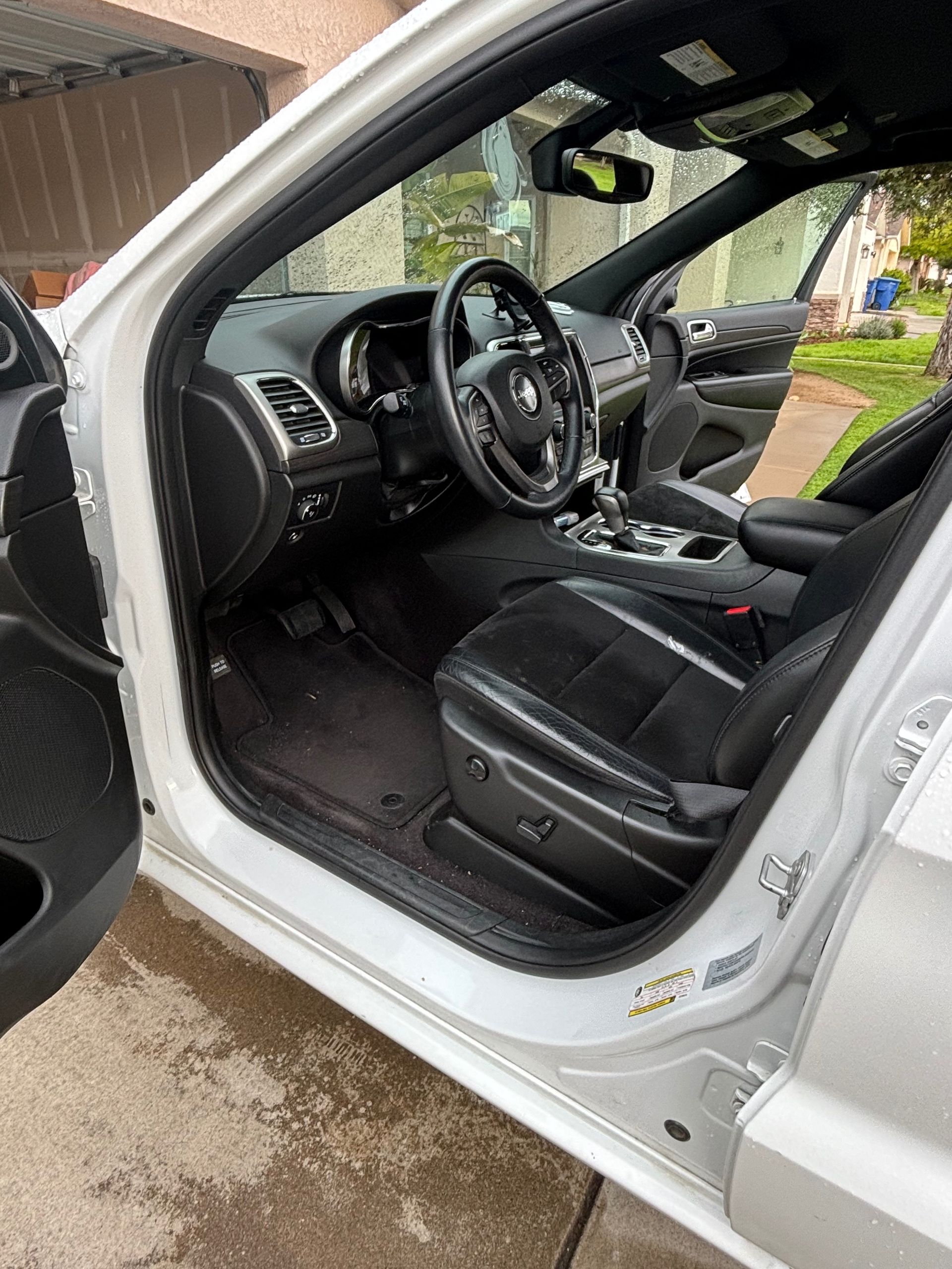 Open driver’s door showing a black leather car interior and steering wheel.