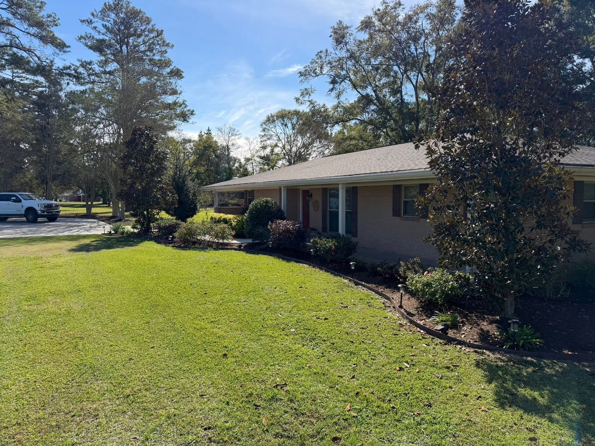 Suburban house with a green lawn, trees, and clear blue sky