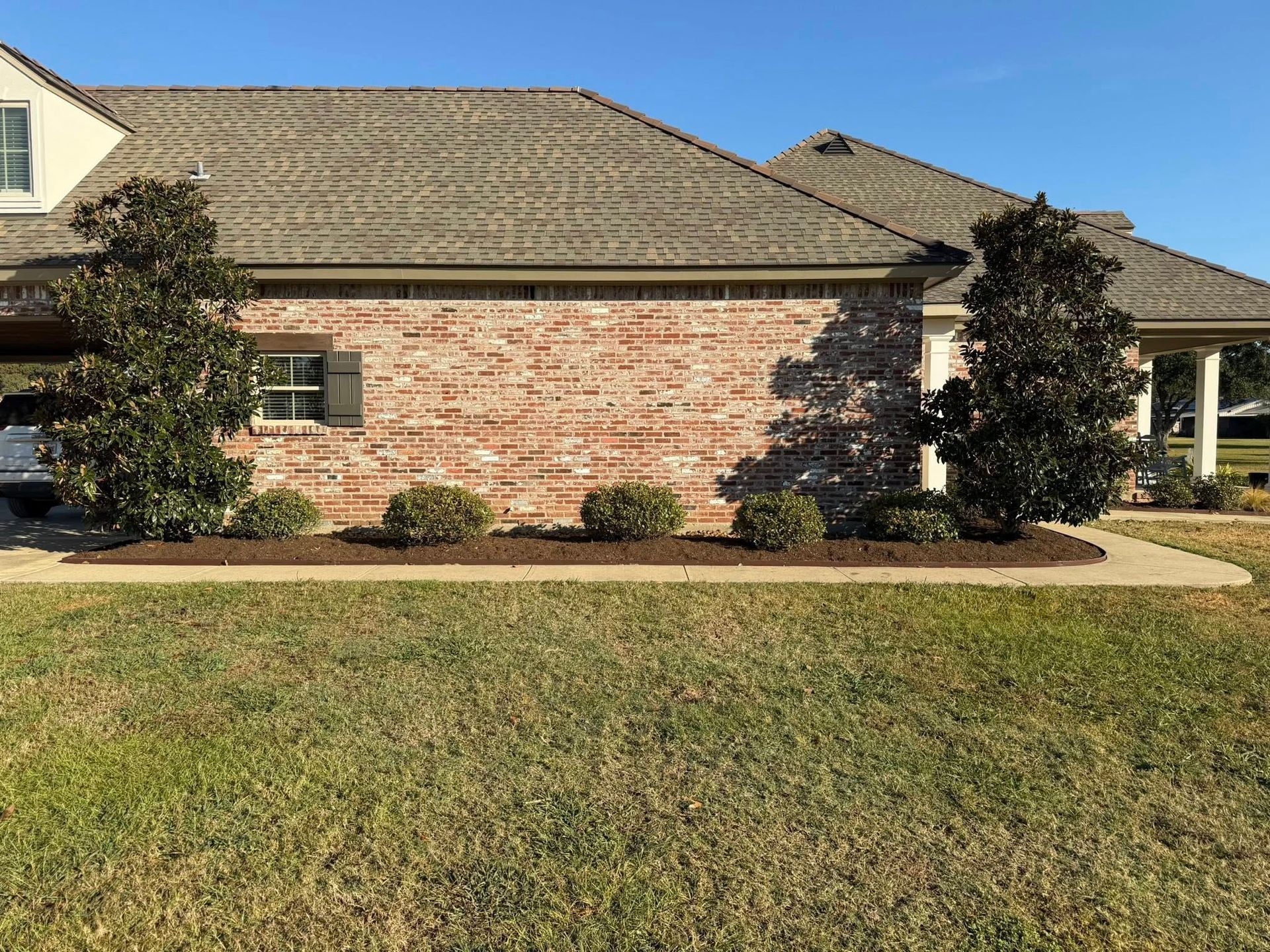 Single-story brick house with a tiled roof and front lawn under a clear sky