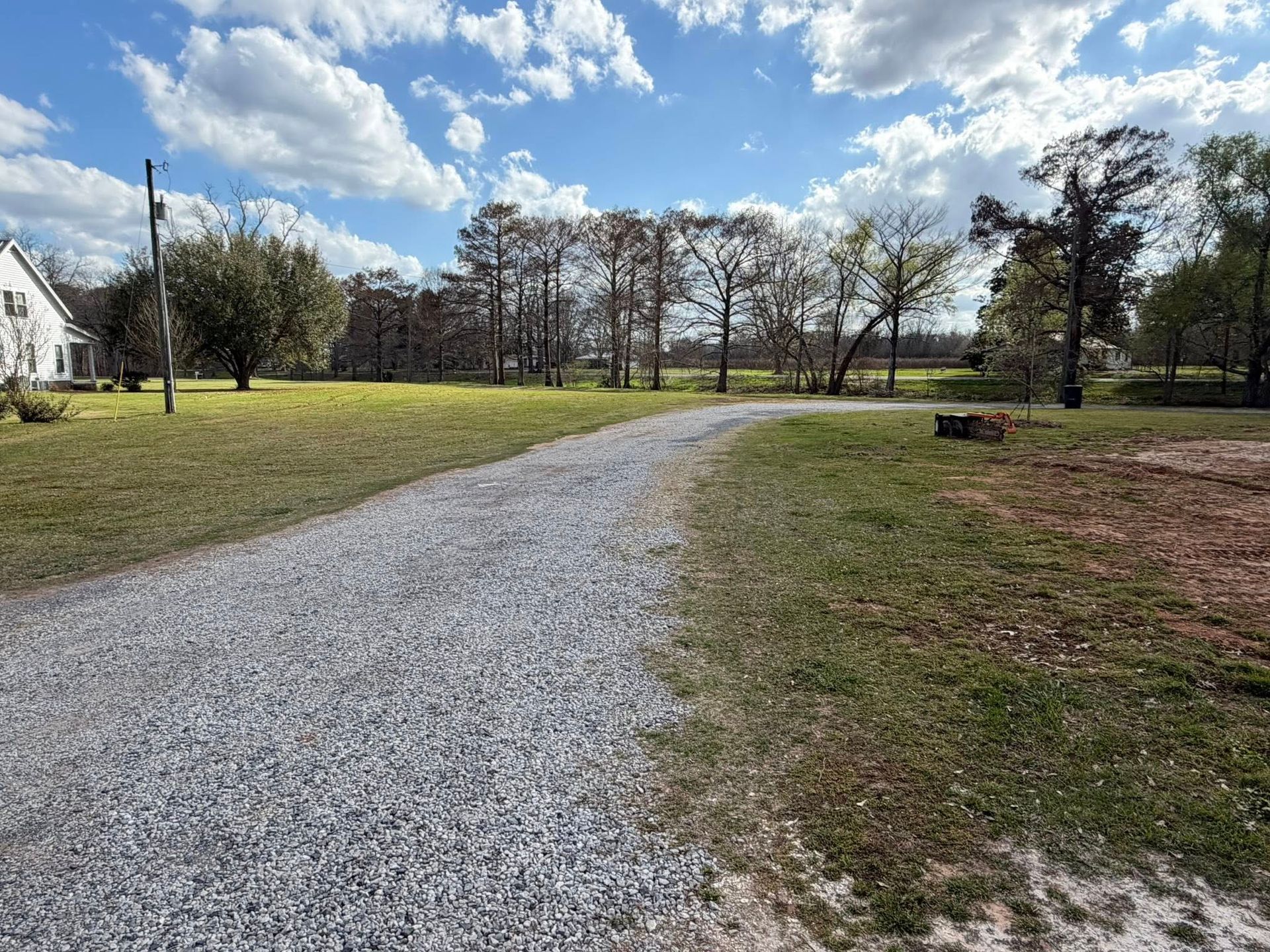 Gravel driveway curving through a grassy park under a partly cloudy sky