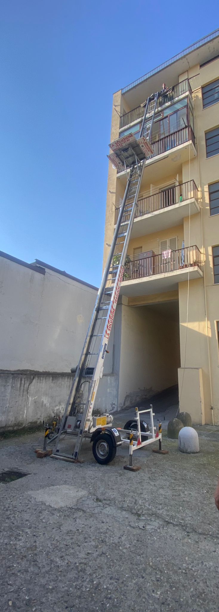 Un edificio con una scala per camion che si estende fino a un balcone in una giornata di sole.