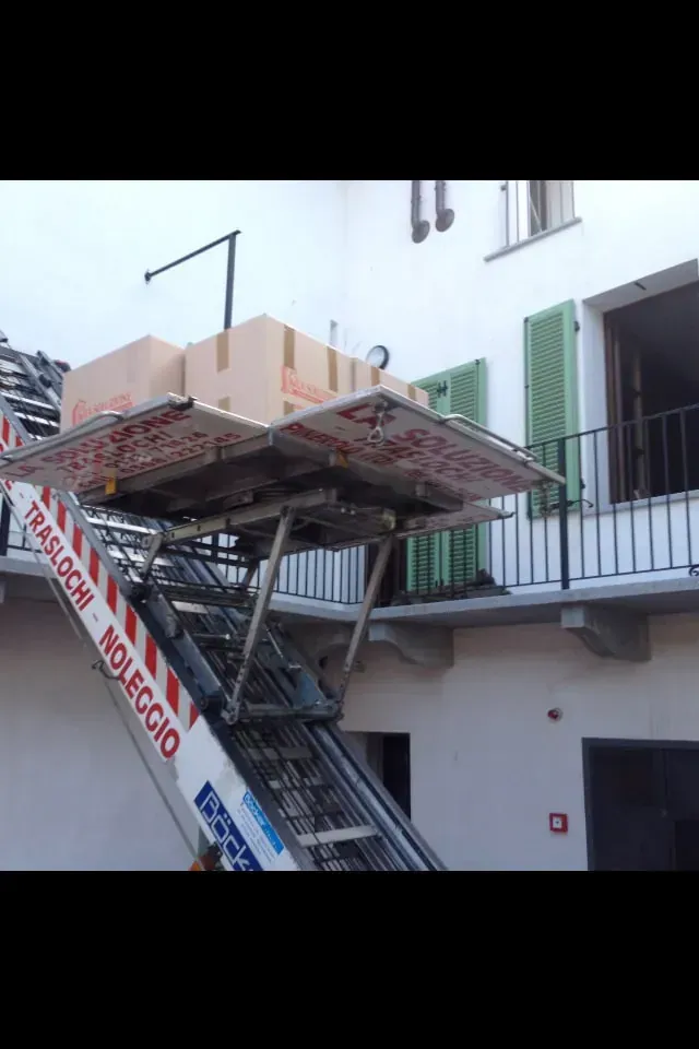 Trasloco di scatoloni su una piattaforma elevatrice accanto a un edificio.
