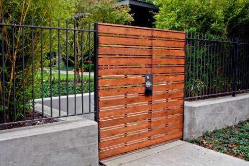 A Wooden Gate Is Surrounded By A Metal Fence – Mishawaka IN - Milestone Fence