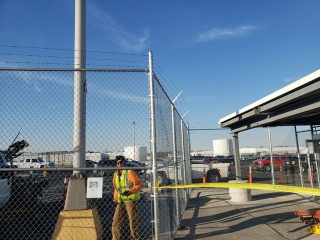 A Man In A Yellow Vest Stands In Front Of A Chain Link Fence – Mishawaka IN - Milestone Fence