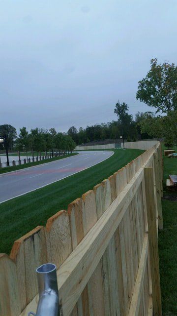 A Wooden Fence Surrounds A Lush Green Field With A Road In The Background – Mishawaka IN - Milestone Fence