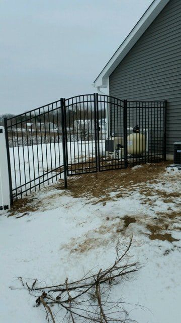 A Metal Fence Surrounds A Snowy Yard In Front Of A House – Mishawaka IN - Milestone Fence