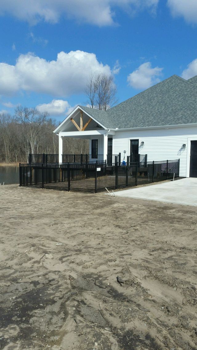 A White House With A Fence Around It And A Lake In The Background – Mishawaka IN - Milestone Fence