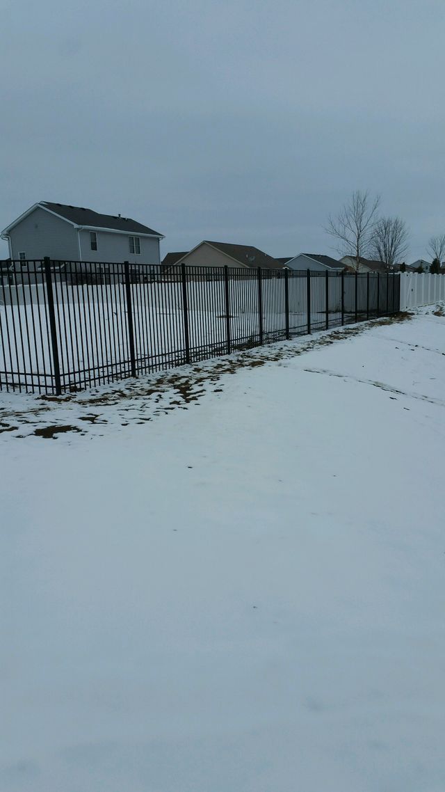A Snowy Field With A Fence In The Foreground And Houses In The Background – Mishawaka IN - Milestone Fence