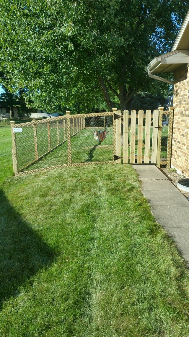 A Wooden Fence Surrounds A Lush Green Yard Next To A Sidewalk – Mishawaka IN - Milestone Fence