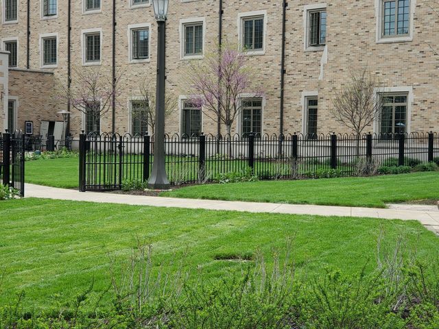 A Large Brick Building With A Lush Green Lawn In Front Of It – Mishawaka IN - Milestone Fence