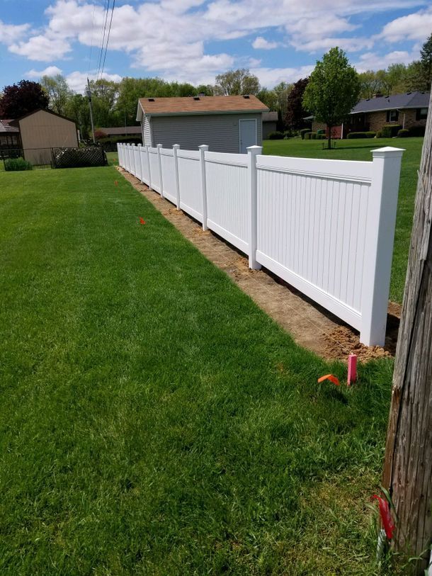 A White Fence Is Sitting In The Middle Of A Lush Green Field – Mishawaka IN - Milestone Fence