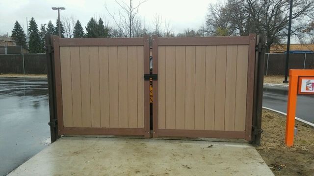 A Wooden Gate Is Sitting On A Sidewalk Next To A Road – Mishawaka IN - Milestone Fence