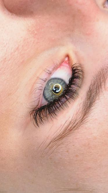 Close-up of a green eye with long eyelashes and light brown eyebrow