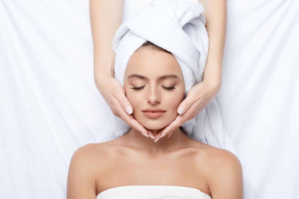 Woman receiving a facial massage with a towel wrapped around her head