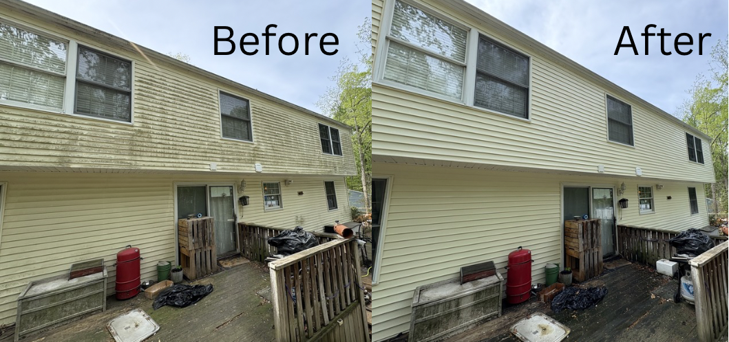 Hand spraying water onto concrete steps beside a stone wall and black iron fence